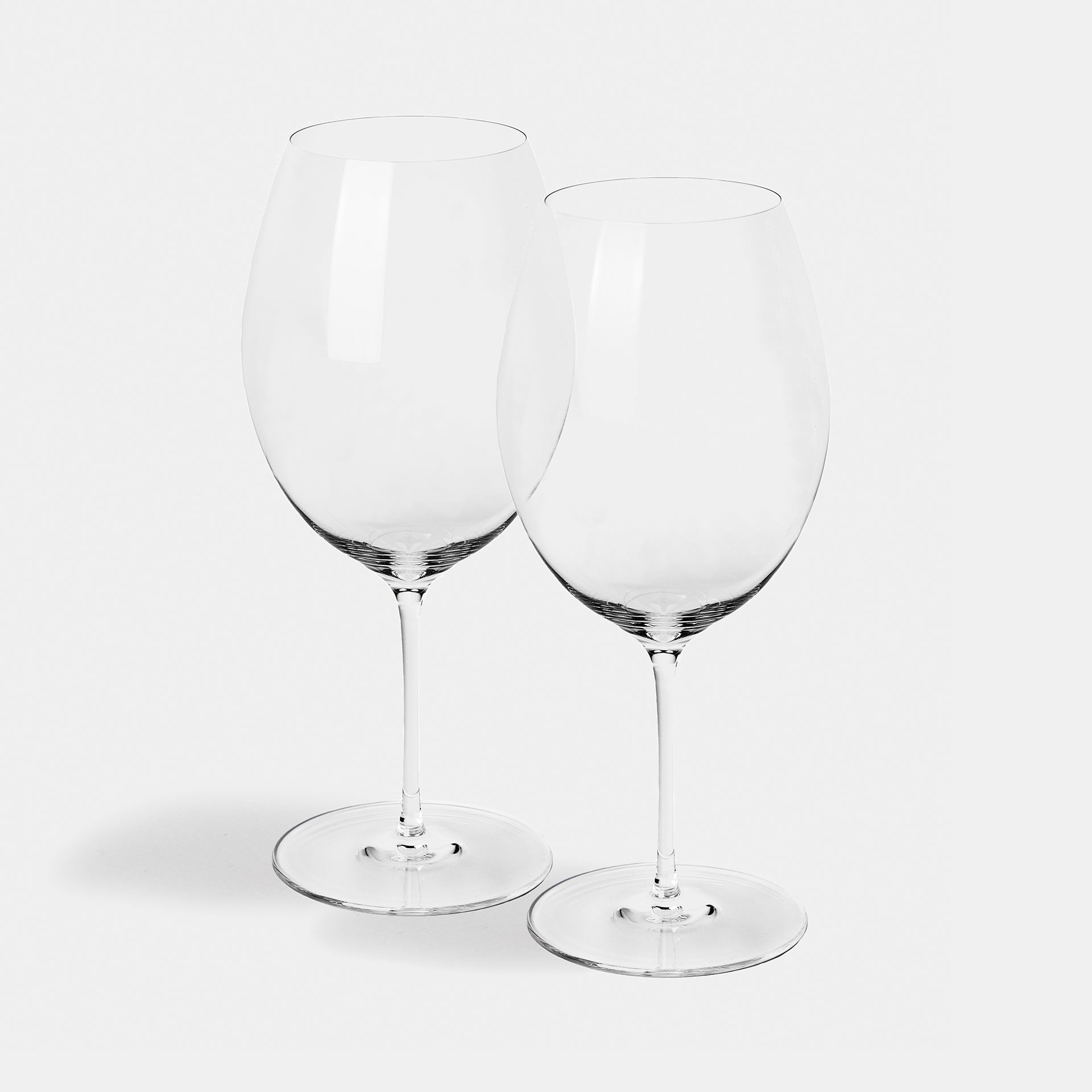A pair of tall bordeaux glasses with deep bowls, shown together.