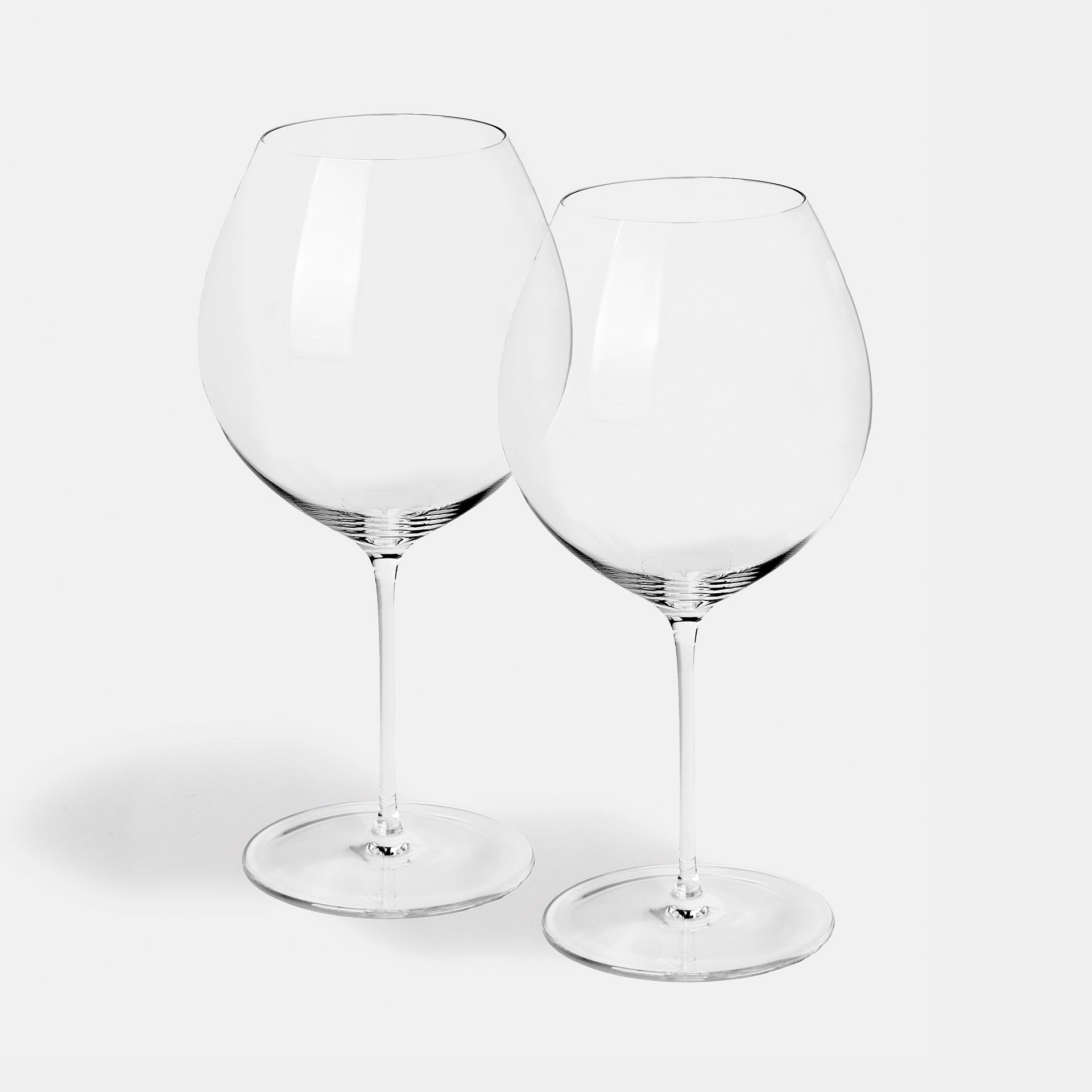 A pair of wide-bowled burgundy glasses, shown together.